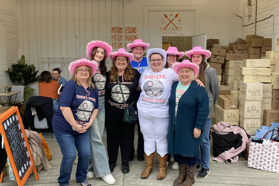 Hen party group outside The Craft Pottery wearing pink fluffy cowboy hats and Bride wearing white fluffy cowboy hat